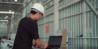 一名亚洲男子在仓库使用笔记本电脑
