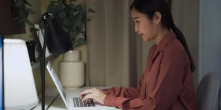年轻女性晚上在家使用笔记本电脑工作