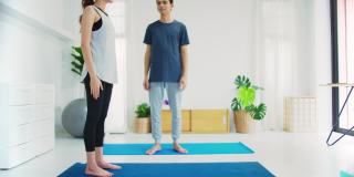 亚洲年轻情侣夫妇玩瑜伽和一起锻炼在家里的背景。锻炼身体，增加柔韧性，收紧体型。4 k慢动作。