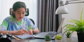 亚洲少女使用平板电脑，同时在家在线学习。