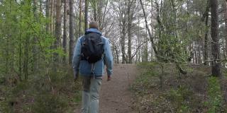 让徒步旅行者走在森林的小上坡路上