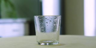 在一个家庭内部，冰块掉进了厨房的玻璃杯里。适当的营养。360度旋转框架。缓慢的运动。