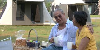 亚洲老夫妇坐在露营放松和喝一杯咖啡