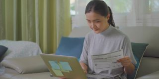 亚洲女性在家里用笔记本电脑付账
