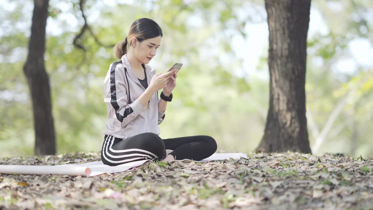 亚洲青少年穿着运动裤在公园里发短信