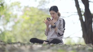亚洲青少年穿着运动裤在公园里玩手机视频素材模板下载