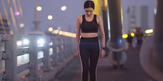 亚洲少女在桥上做膝盖练习在城市健身运动服