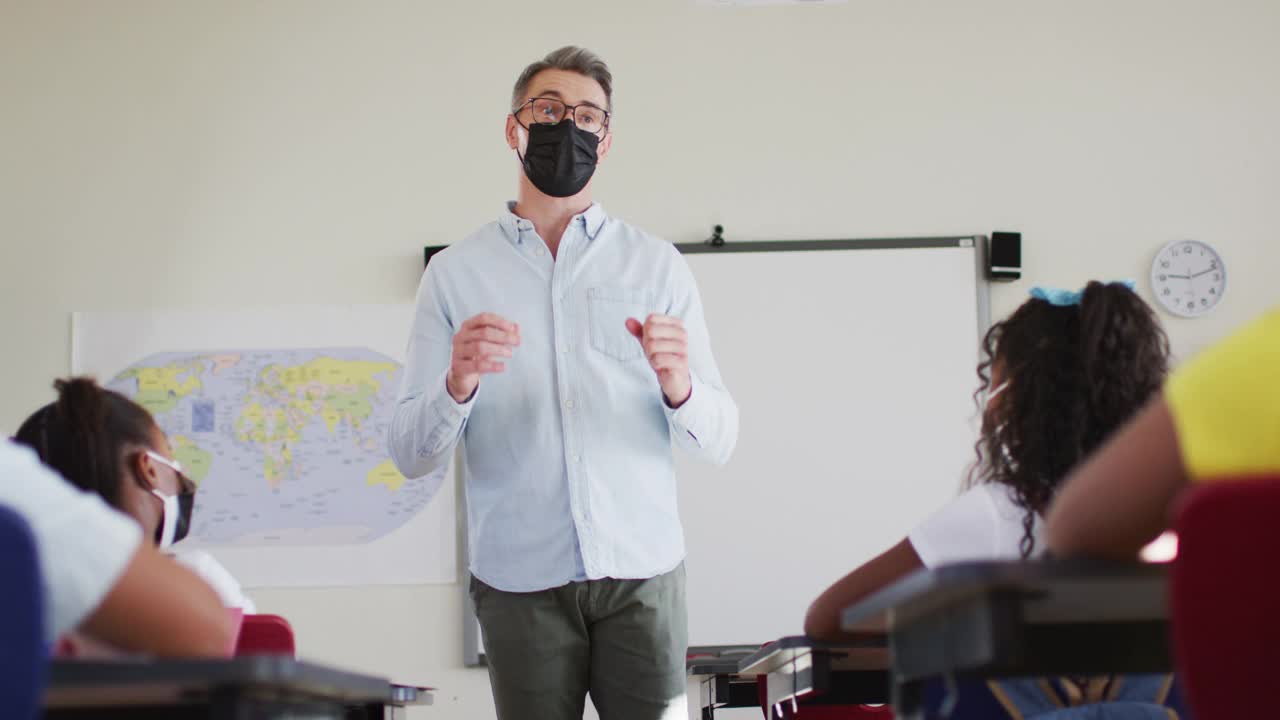 白人男老师戴着口罩在学校上课