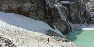 阿尔卑斯山景观的超断层。在山峰之间的绿松石湖边慢跑的女人。