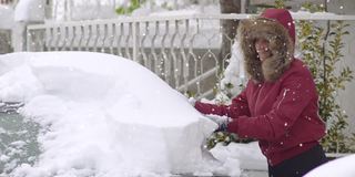 一场暴风雪过后，一名妇女困在雪中，正在从车上铲雪