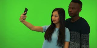 一名年轻的亚洲女子和一名年轻的黑人男子在绿幕摄影棚自拍