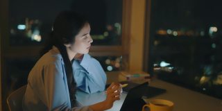 一名女子晚上在办公室用电子平板电脑工作