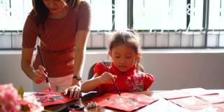 亚洲华人家庭在红纸上书写中国书法