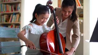 年轻的亚洲女孩学习拉大提琴视频素材模板下载