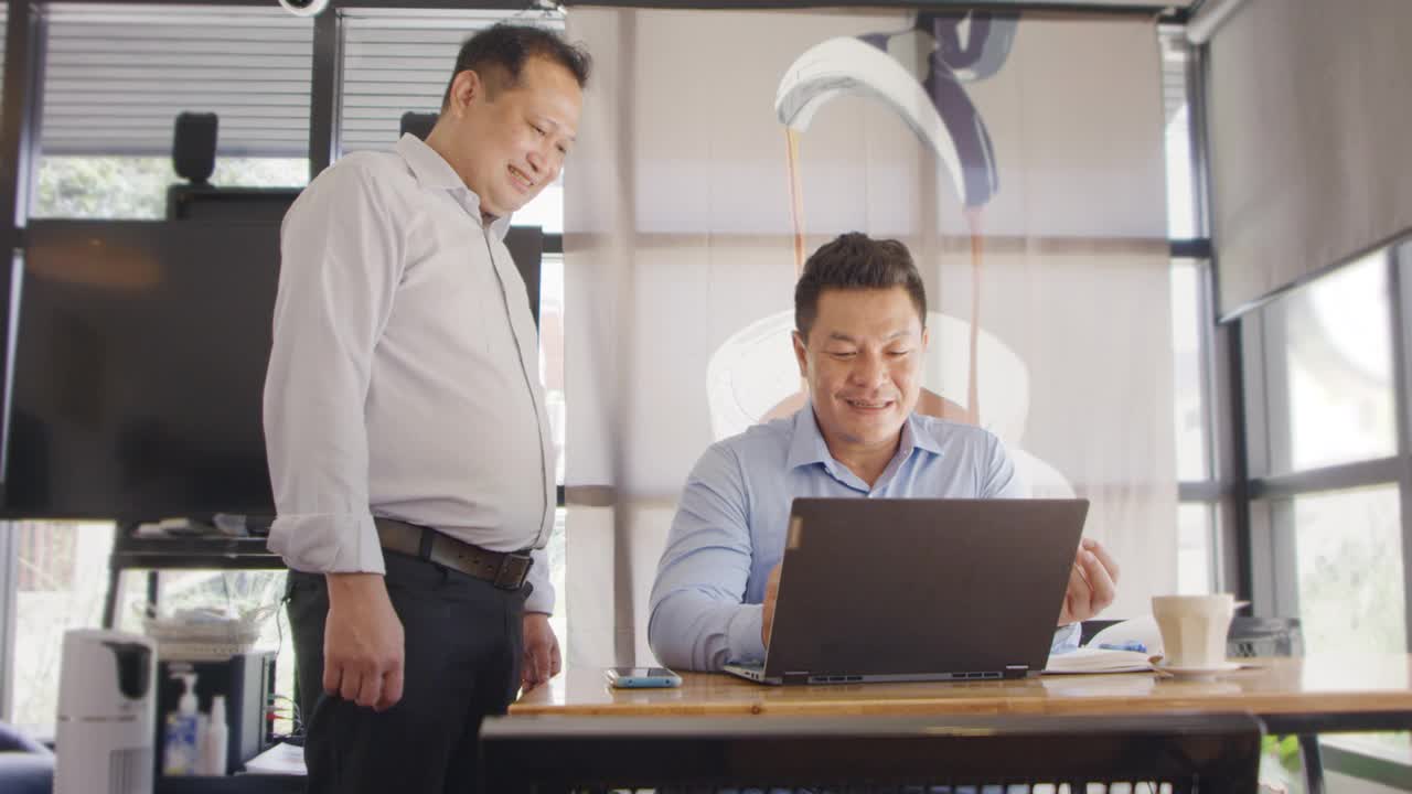 两个商人在办公室里用笔记本电脑一起工作