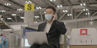 亚洲精力充沛的商人，戴着防护面罩，在等待飞机到达机场期间，接听电话，从合作伙伴那里获得关于新想法的信息-股票视频
