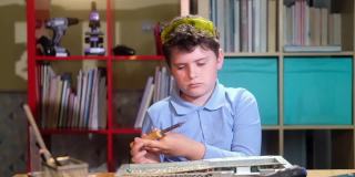 学生男孩焊接芯片和观看视频与说明笔记本电脑