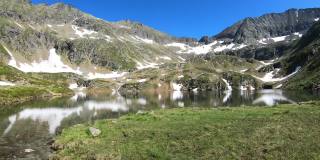 这是一个平静的湖，隐藏在奥地利阿尔卑斯山的高处，在Schladming附近。融雪使湖的面积增大了。山坡上有很多雪原。郁郁葱葱的山坡上。早春。宁静