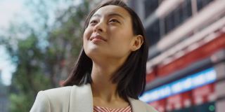 美丽的日本女性的肖像穿着漂亮的休闲衣服在街上摆姿势。在大城市生活的成功女性。背景与办公楼和广告牌。