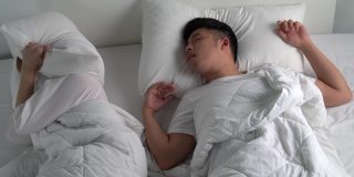 年轻的亚洲男人在床上睡觉时打鼾。