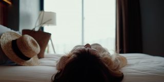 疲惫的女人享受在她的酒店房间柔软的床。