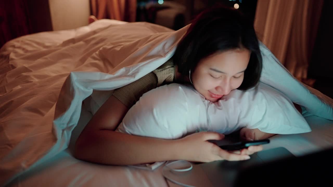 睡眼惺忪的女人在床上玩社交媒体。