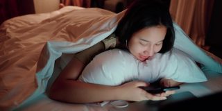 睡眼惺忪的女人在床上玩社交媒体。