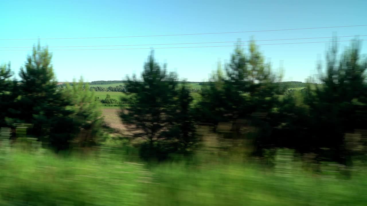 在夏日阳光明媚的日子里，透过车窗可以看到绿色的乡村田野和清澈的蓝天。旅行，旅行，开车旅行。运输
