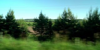 在夏日阳光明媚的日子里，透过车窗可以看到绿色的乡村田野和清澈的蓝天。旅行，旅行，开车旅行。运输