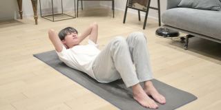 年轻的亚洲男子在家做瑜伽垫