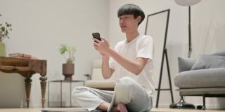 一名亚洲男子在瑜伽垫上用智能手机视频通话