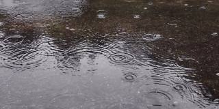 雨水落在柏油路上的大水坑里，淹没了道路。雨季的雨水落在混凝土地板上。