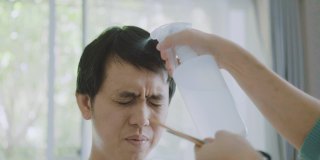 一位亚洲妇女在家为丈夫理发。