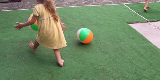 在炎热的夏天，快乐可爱的幼儿园小朋友们玩着五颜六色的球。孩子们在院子里玩耍。宝宝在花园在阳光明媚的一天户外。童年、职业、亲子、家庭观念