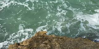 岩石海岸上的海浪。暴风雨的海景。蓝绿色海水表面。