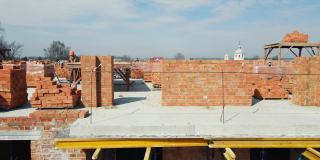 两个建筑工在一座多层建筑上铺设砖墙