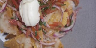 一盘新鲜的墨西哥玉米片，配上洋葱、番茄、墨西哥胡椒、奶酪和酱汁。传统的墨西哥开胃小吃