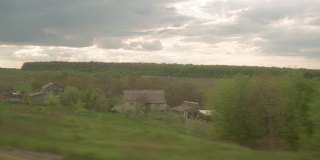 从高速列车的窗口看风景美丽的自然田野公路与汽车和森林在傍晚黄昏天空日落在夏季背景。交通、旅游、铁路、通讯理念