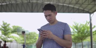 年轻人在篮球场使用手机。