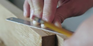 木匠用尺子和铅笔在木板上做记号。木工的艺术手工木工工具的声音