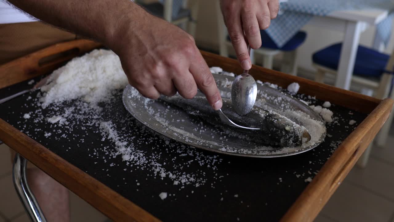 服务员在餐厅用餐时用叉子和勺子清洗鲈鱼皮