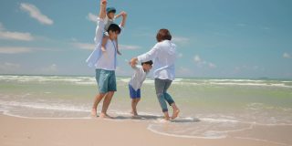 亚洲的爸爸和妈妈在夏天的一天和孩子在海滩上玩。父母和孩子们去海边度假。幸福家庭关系理念。慢动作镜头