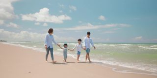 亚洲的爸爸和妈妈在夏天和孩子一起玩，沿着海滩散步。父母和孩子们去海边度假。幸福家庭关系理念。后视图和慢动作