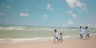 亚洲父亲和母亲在暑假沿着海滩追逐孩子。父母和孩子们去海边度假。幸福的家庭关系和团队合作理念。慢动作镜头