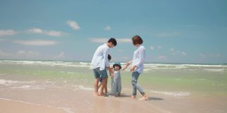 亚洲的爸爸和妈妈在夏天的一天和孩子在海滩上玩。父母和孩子们去海边度假。幸福家庭关系理念。慢动作镜头