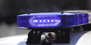 在城市交通环境中，犯罪现场上开着蓝色灯的警车。