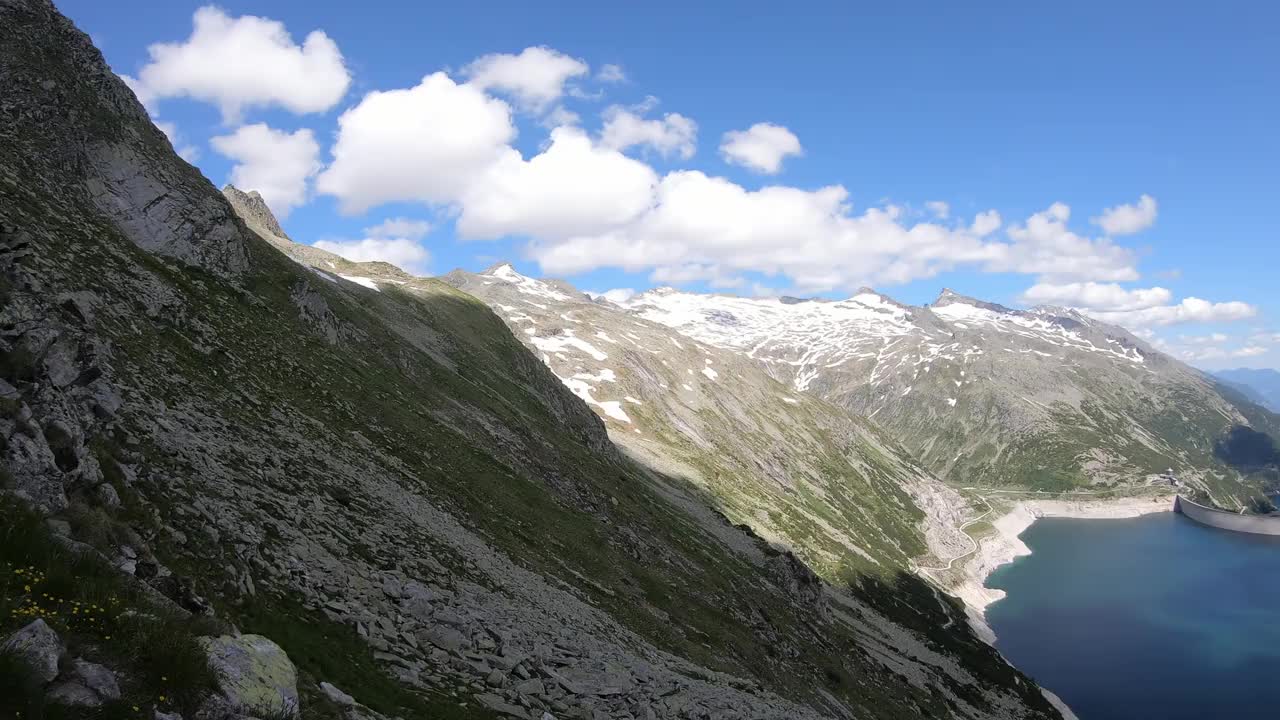 全景式的人工湖在科隆布雷因大坝在卡林西亚，奥地利。大坝被高山积雪覆盖的山峰包围着。陡峭的斜坡。这个湖是深蓝色的。自然能源