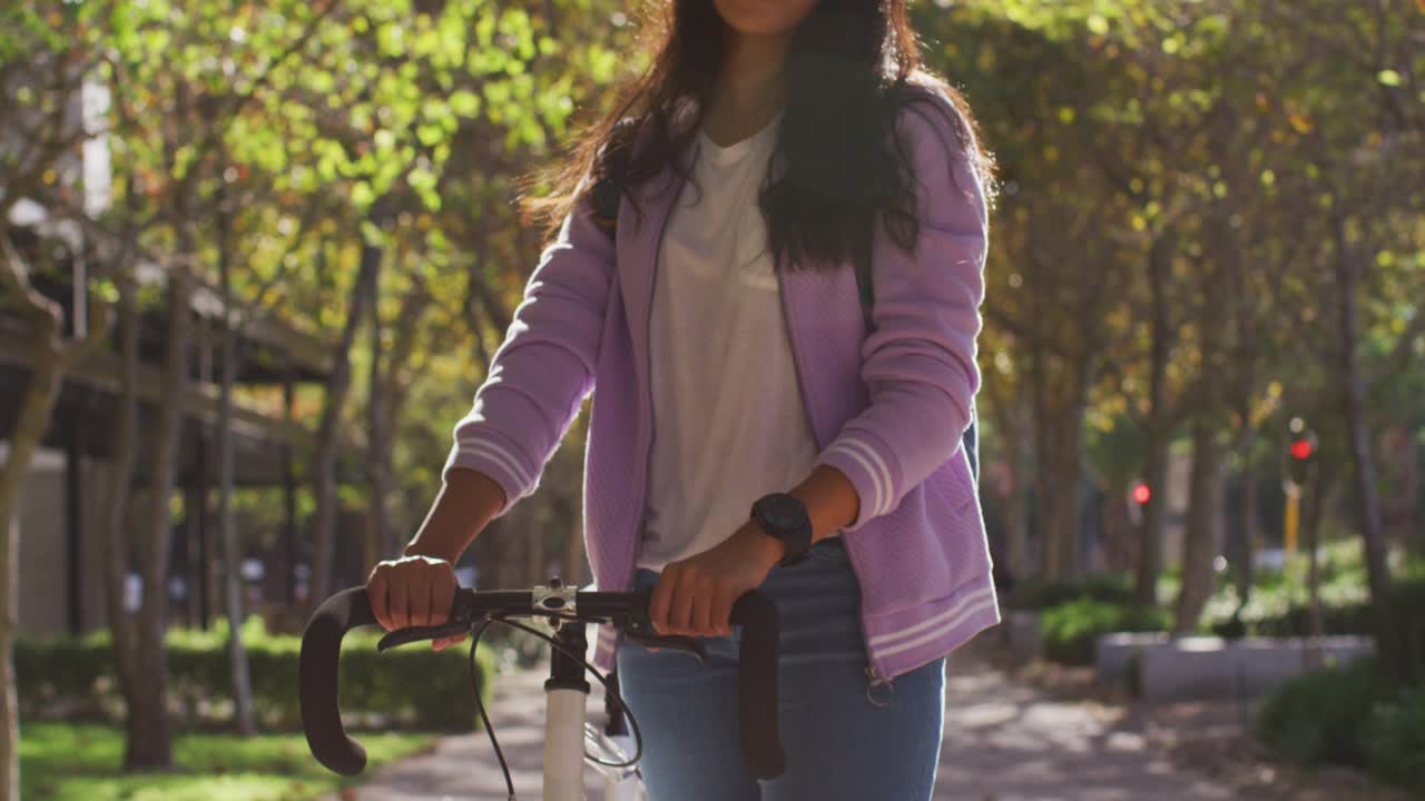 亚洲妇女的肖像与自行车微笑而站在公园