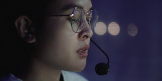 亚洲女性呼叫中心话务员通过耳机通话