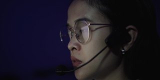 亚洲女性呼叫中心话务员通过耳机通话